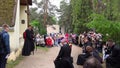 Cardinal priest in soutane and believers people group kneel and pray near chapel