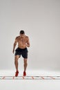 Cardio exercises. Full length shot of young athletic man training on agility ladder drill isolated over grey background Royalty Free Stock Photo