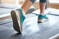 Cardio workout. Cropped photo of woman in sports shoes running on treadmill at gym