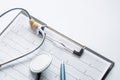 Cardiogram with stethoscope, pen, magnifier, pills and glasses lay on a table