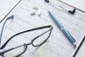 Cardiogram with stethoscope, pen, magnifier, pills and glasses lay on a table