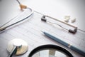 Cardiogram with stethoscope, pen, magnifier, pills and glasses lay on a table