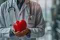 A cardiologist doctor delicately cradles a red heart in his hands, conveying a powerful image resonant with the concept of cardiac Royalty Free Stock Photo