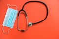 Cardiologist doctor tool.Medical mask, stethoscope top view on bright orange background.