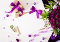 Cards and flowers, box gift,violet ribbon and cloth lying on a white table Royalty Free Stock Photo