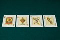 Cards of the four aces of the Spanish bajara on a green game mat. With the four triumphs: golds, cups, swords and sticks