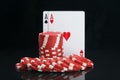 Cards of the highest denomination for the game of poker, on a black background with a reflection, along with red chips