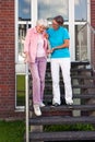 Care assistant helping a senior lady on steps.