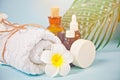 Care, beauty and spa concept. Organic soap, small bottles with essential oils, white towel, palm leaf, plumeria frangipani flower