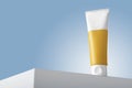 Care cream tube mockup on white table or podium, blue backdrop. Blank yellow label. Sunscreen treatment cosmetics template, copy