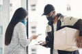 Care enough to keep it contact free. Shot of a masked young man and woman using smartphones during a home delivery.