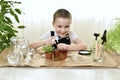 Care for micro greens. The boy giggles softly and splashes water on pots of plants. Spraying from a spray bottle