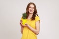 Care for potted plant. Portrait of young woman in yellow T-shirt holding flower pot with cactus Royalty Free Stock Photo