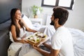 Happy young couple have breakfast at the bed. Care and romance at the morning. Royalty Free Stock Photo