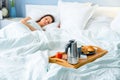 Surprised and happy young woman lying at the bed with breakfast on tray Royalty Free Stock Photo