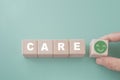 care text and green smiling face on wooden cube block with hand on green background including copy space for health care, health