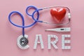 CARE word made from medicine pills and stethoscope, temperature, red heart on pink background. Concept of Valentine`s Day Royalty Free Stock Photo