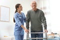 Care worker helping elderly man with walker in hospice