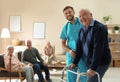 Care worker helping to elderly man with walker in hospice Royalty Free Stock Photo