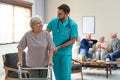 Care worker helping to elderly woman with walker in hospice Royalty Free Stock Photo