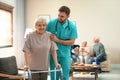 Care worker helping to elderly woman with walker in hospice Royalty Free Stock Photo