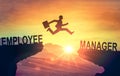 Career jump. Silhouette of man jumping from employee cliff to manager cliff against backdrop of sunset sky. Motivation for career