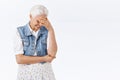 Carefree, amused charming modern granny with grey combed hair in stylish denim vest, dress, laughing over hilarious kid