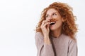 Carefree, arrogant and self-assured elegant, funny redhead woman with curly hair holding strand and put it under nose to