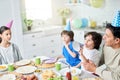 Carefree athmosphere. Joyful little boy playing with his birthday cap. Hispanic family having dinner while celebrating Royalty Free Stock Photo