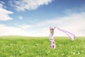 Carefree beautiful Asian woman holding fabric on green meadow