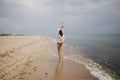 Carefree beautiful woman in knitted sweater and with windy hair running on sandy beach at cold sea, having fun. Stylish young sexy Royalty Free Stock Photo