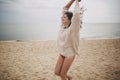 Carefree beautiful woman with windy hair running on sandy beach at cold sea waves, having fun. Stylish young happy female in Royalty Free Stock Photo