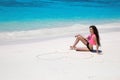 Carefree bikini model girl with heart on sand relaxing on exotic