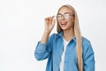 Carefree blond girl laughing, smiling and looking happy, put on glasses, standing in casual outfit over white background Royalty Free Stock Photo