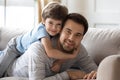 Carefree boy cuddling smiling dad, looking at camera. Royalty Free Stock Photo