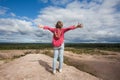 Carefree child girl with hands up against sky clouds outdoors