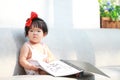 Carefree Chinese baby girl hold a menu on sofa Royalty Free Stock Photo