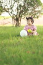 Carefree Chinese baby girl play a ball and balloon on the lawn