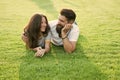 Carefree couple enjoying sunny day relaxing on green meadow, romantic date concept Royalty Free Stock Photo