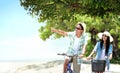 Carefree couple having fun and smiling riding bicycle at the beach