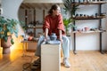 Carefree creative female potter sits and looking away resting after shaping raw clay crockery