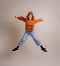 Carefree ecstatic beautiful woman with arms outstretched jumping in air against background