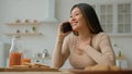 Carefree ethnic Asian woman housewife talking mobile phone in kitchen talk with friend calling speak cellphone share Royalty Free Stock Photo