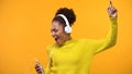 Carefree female millennial singing on bright background wearing headphones, fun