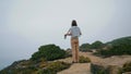 Carefree girl look ocean resting on rocky cliff. Relaxed tourist enjoy vacation