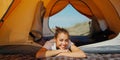 carefree girl lying in tent and enjoying sunny day during camping weekend