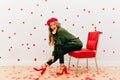 Carefree girl wears soft green shirt sitting in red chair. Portrait of adorable long-haired woman in french hat isolated
