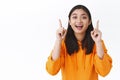 Carefree happy healthy asian girl in orange hoodie inviting to click page, follow company or download something