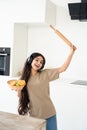 Carefree happy housewife dancing with headphones in modern kitchen