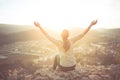 Carefree happy woman sitting on top of mountain edge cliff enjoying sun on her face raising hands in sunlight rays. Enjoying natur Royalty Free Stock Photo
